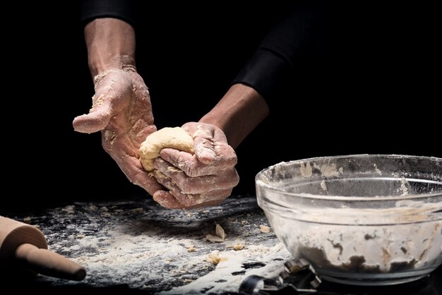 Prodotti a base di farina Primo piano di giovani mani cucinare prodotti da forno e impastare la pasta mentre si lavora come chef.