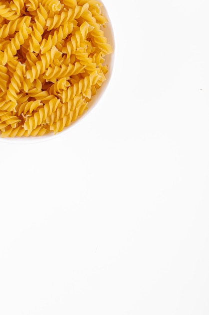 Prodotti a base di pasta a forma di spirale su una trama di piatto su sfondo bianco