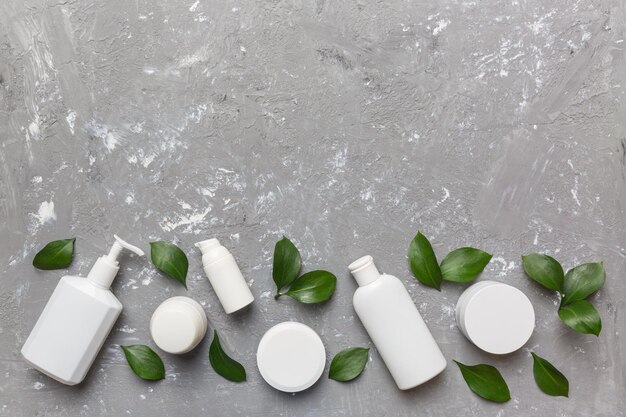 Prodotti cosmetici biologici con foglie verdi su fondo di cemento Copia spazio piatto