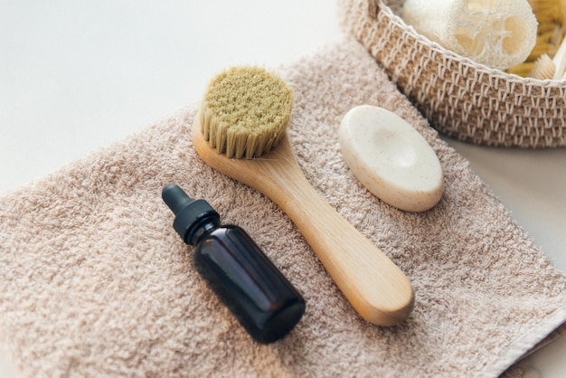 Prodotti cosmetici in asciugamano da bagno siero flacone caduto spazzola per il viso e sapone esfoliante