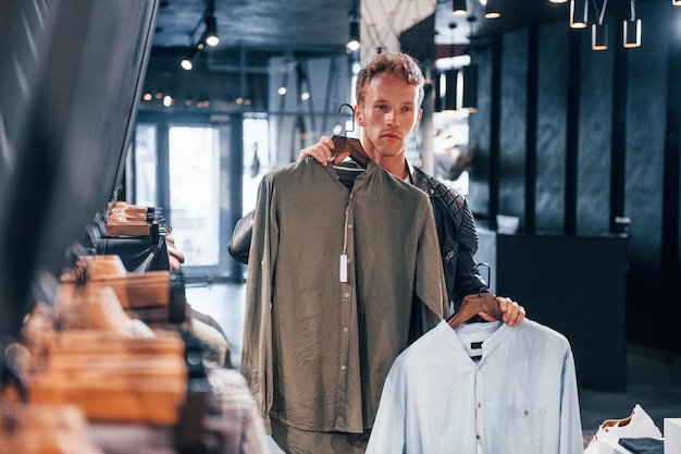 Prodotti di qualità Ragazzo giovane in un negozio moderno con vestiti nuovi Abbigliamento elegante e costoso per gli uomini