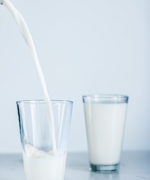 Prodotti lattiero-caseari nutrizione sana e concetto di colazione giornata mondiale del latte versando in vetro sul tavolo di marmo