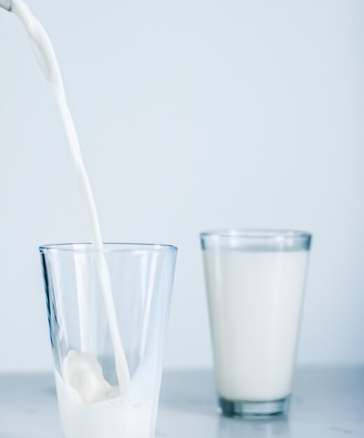 Prodotti lattiero-caseari nutrizione sana e concetto di colazione giornata mondiale del latte versando in vetro sul tavolo di marmo