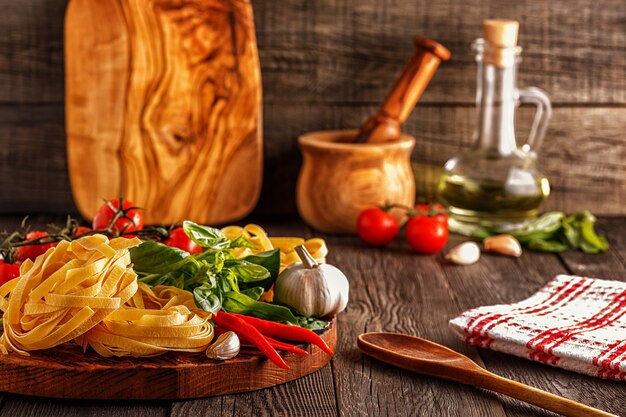 Prodotti per cucinare pasta, pomodori, aglio, pepe e basilico sul vecchio fondo di legno