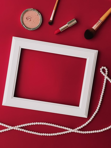 Prodotti per il trucco con cornice artistica orizzontale bianca e gioielli di perle su sfondo rosso come grafica di design flatlay stampa o concetto di album fotografico