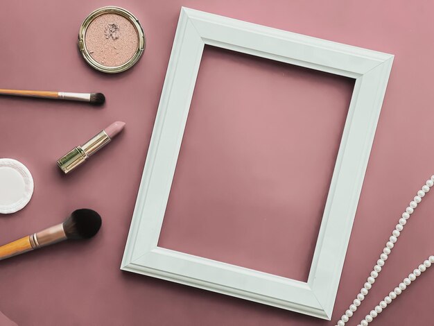 Prodotti per il trucco con cornice verticale e gioielli di perle su sfondo rosa cipria come stampa di opere d'arte dal design piatto o album fotografico