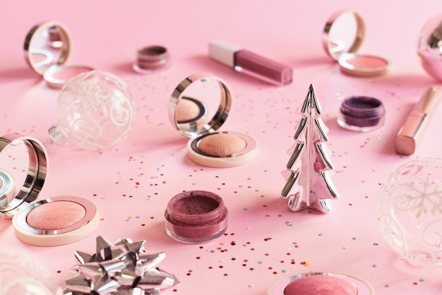 Prodotti per il trucco su sfondo rosa Cosmetici per il trucco della festa di Natale o Capodanno