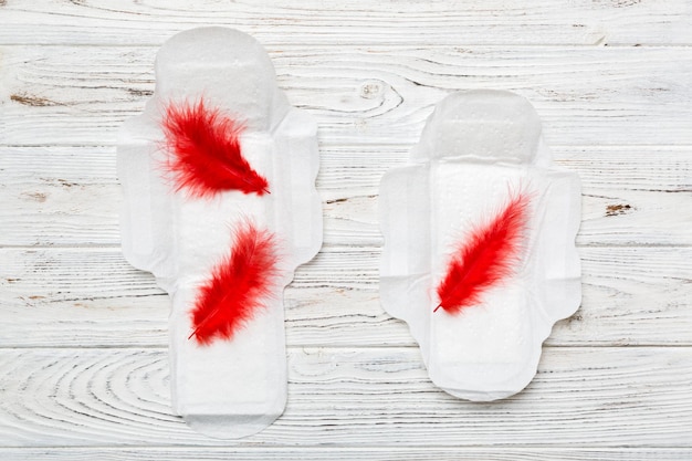 Prodotti per l'igiene delle donne o assorbenti con piuma rossa su sfondo colorato Colore pastello Primo piano Posto vuoto per il testo Igiene quotidiana femminile