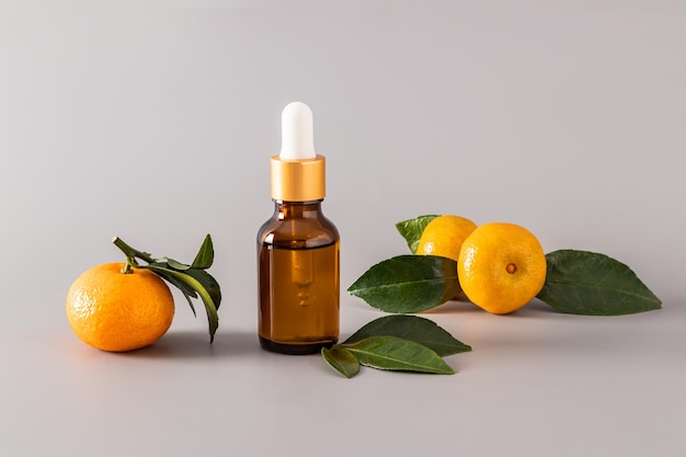 Prodotto cosmetico in bottiglia con contagocce tra mandarini maturi su sfondo pastello concetto di bellezza e cosmetici naturali Vitamina C