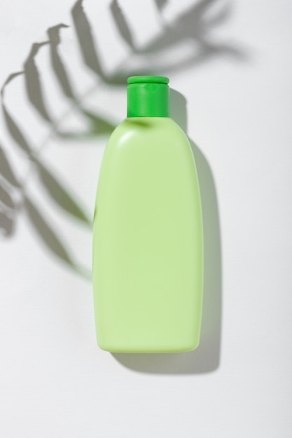 Prodotto cosmetico in tubo verde con spazio vuoto per etichetta di branding. Cosmetici naturali per la cura della pelle e dei capelli. Shampoo o lozione con ombretto fogliare su sfondo bianco