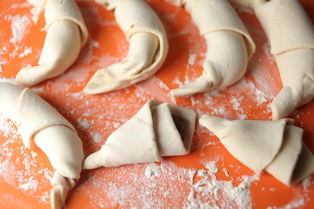 Produzione di croissant classici. Involtini di mezzaluna prima di infornare. croissant su un vassoio. Pasticceria francese, prodotti da forno. Impasto per croissant. Preparazione dei croissant.