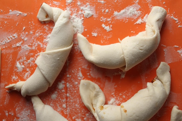 Produzione di croissant classici. Involtini di mezzaluna prima di infornare. croissant su un vassoio. Pasticceria francese, prodotti da forno. Impasto per croissant. Preparazione dei croissant.