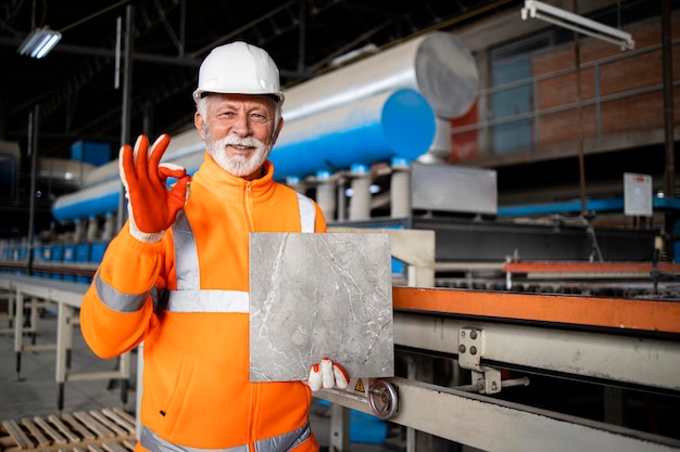 Produzione di piastrelle di ceramica di successo e operaio che tiene il prodotto.