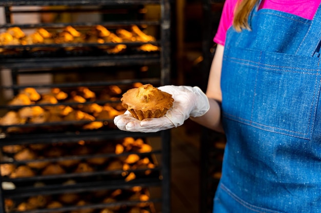 Produzione di prodotti da forno Giovane panettiere che tiene in mano il cupcake nella panetteria
