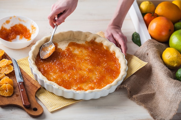 Produzione di torta con marmellata di agrumi e fettine di mandarino