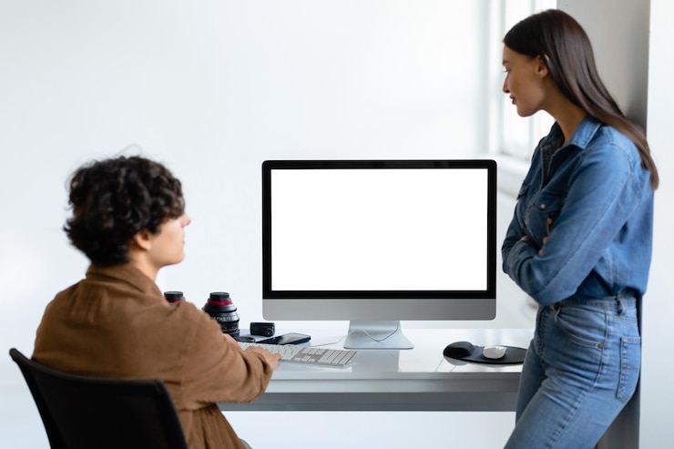 Photo professional male photographer and female assistant or art director discussing photos on computer monitor in photostudio