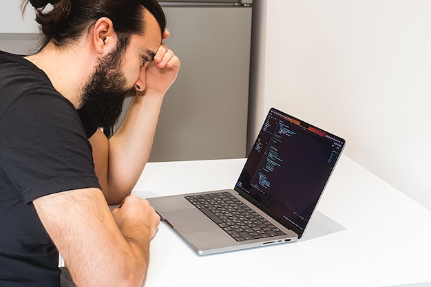 Professional software engineer IT specialist working from home and writing code on a laptop comput