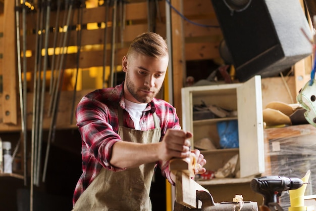 professione, persone, falegnameria, falegnameria e concetto di persone - falegname che lavora con plancia di legno piallatrice in officina