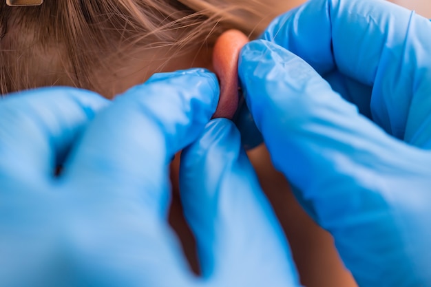 Professionista che tiene il gioiello del piercing appena prima di avvitare la pallina