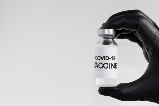 Professionista della salute che tiene la bottiglia di vaccino contro il Covid-19. Assistenza sanitaria e concetto medico.
