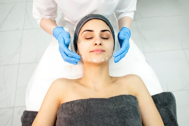 Professionista di cura della pelle in clinica di cosmetologia dermatologo medico applica crema sul paziente039s