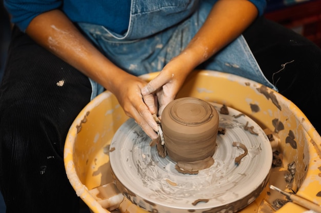 Professionista vasaio artigiano che fa brocca di argilla sul cerchio della ruota del vasaio in officina