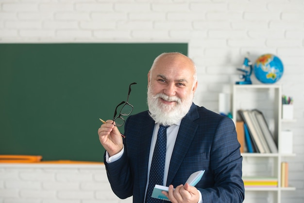 Professore sorridente felice divertente dei capelli grigi nell'aula vuota di lezione