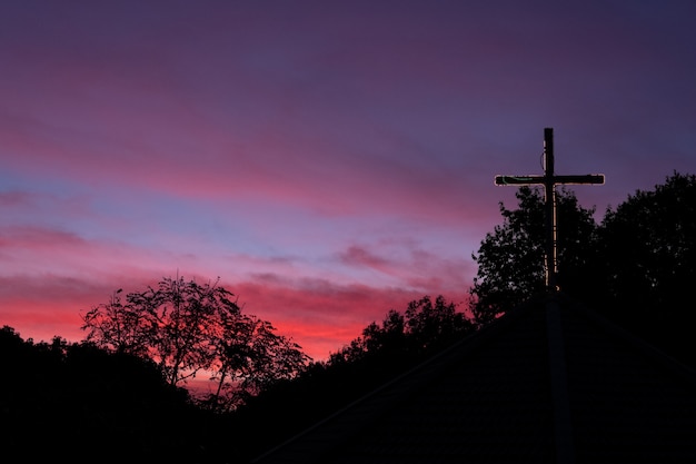 Profili l'incrocio sul tetto della chiesa con il cielo drammatico all'alba.