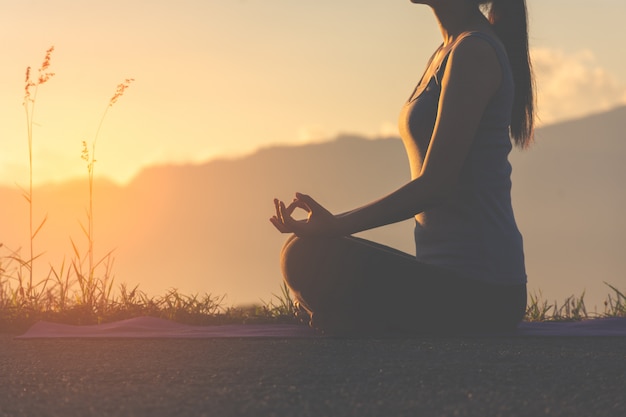 Profili l&#39;yoga di pratica della ragazza di forma fisica sulla montagna con la luce del sole