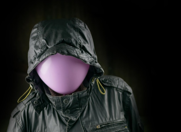 Profili una giacca nera con un palloncino invece di una testa su sfondo nero Il concetto di un criminale in incognito mistero segretezza anonimato