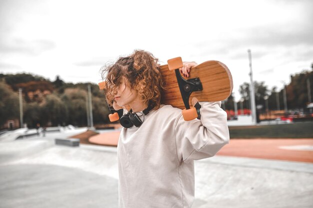 Profilo della ragazza che tiene lo skeetboard sulle sue spalle