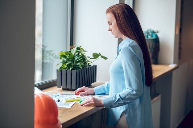 Profilo di donna che lavora con progetti vicino alla finestra