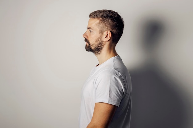 Profilo di un uomo barbuto in piedi su sfondo bianco