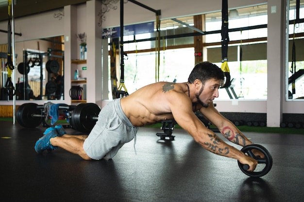 Profilo di un uomo che fa addominali usando un rullo in palestra