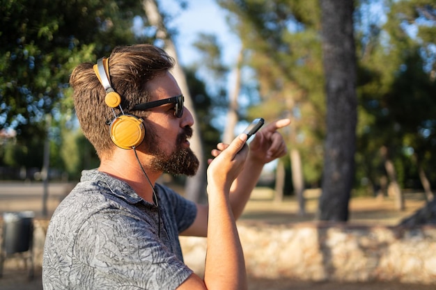 Profilo di un uomo che invia un messaggio vocale con il cellulare all'aperto