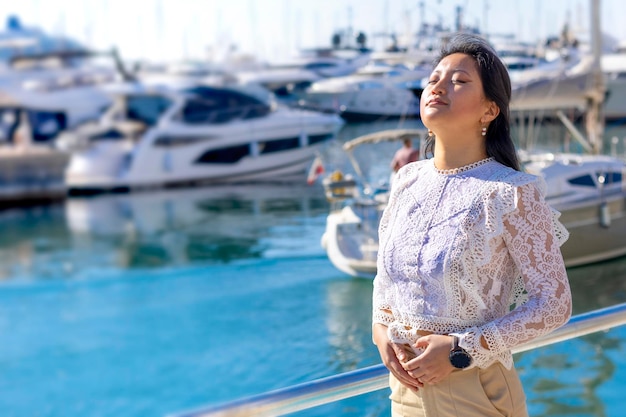 Profilo di una bella donna asiatica che respira aria fresca nel porto marittimo con navi sullo sfondo