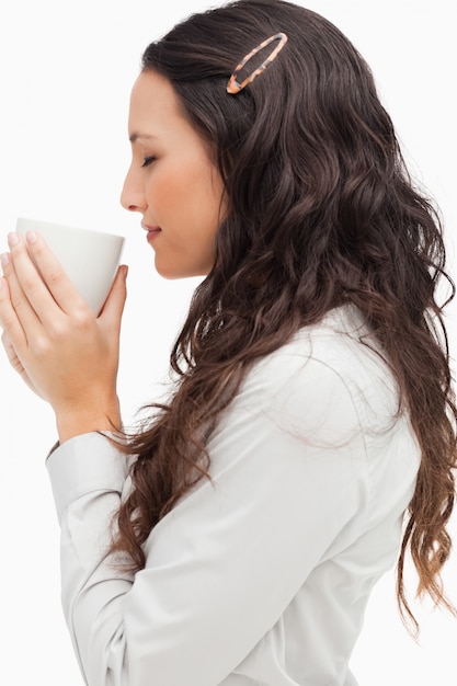 Profilo di una bruna che sente l&#39;odore di un caffè caldo