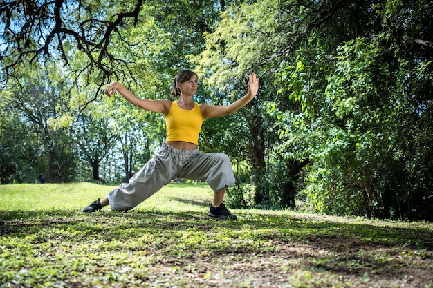 Profilo di una donna che pratica il tai chi circondata da alberi