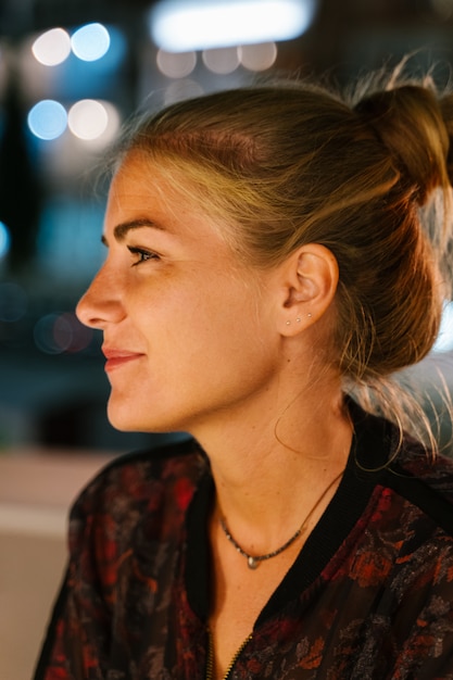 Profilo di una giovane donna bionda su una terrazza di notte