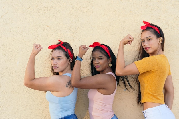 Profilo laterale di tre donne che indossano un velo e mostrano la loro forza con il braccio Concetto di potere femminile e femminismo