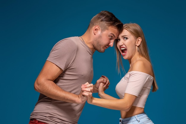 Profilo vista laterale ritratto di uomo e donna arrabbiati in stile casual in piedi, guardandosi e urlando a vicenda.