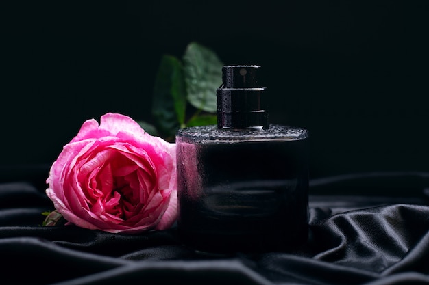 Profumo e fiore rosa su sfondo nero