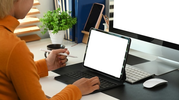 Progettista femminile che tiene penna stilo e lavora con tablet computer sul posto di lavoro creativo.