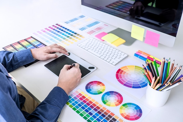 Progettista grafico creativo che lavora sulla selezione dei colori e sui campioni di colore, disegnando sulla tavoletta grafica
