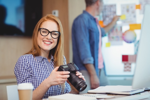 Progettista grafico femminile che tiene macchina fotografica digitale