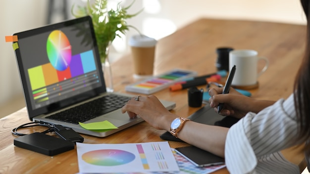 Progettista grafico il suo colore di selezione con il computer portatile e gli accessori creativi sulla tavola.