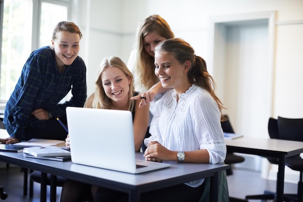 Progetto di squadra Un gruppo di ragazze adolescenti che lavorano su un laptop in classe