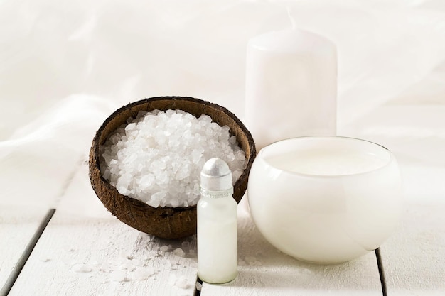 Programma Coconut SPA: sale marino con estratto di cocco, olio di cocco, schiuma, candela profumata su fondo bianco. Messa a fuoco selettiva