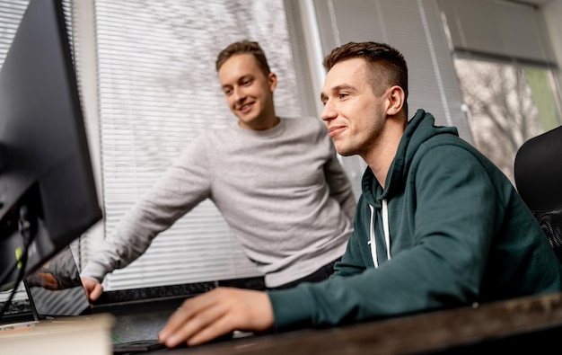 Programmatore bello che lavora in un panno casual al computer. Giovane ragazzo che discute di nuovo progetto.