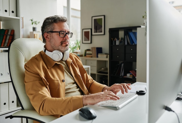 Programmatore dai capelli grigi serio che esamina lo schermo del computer